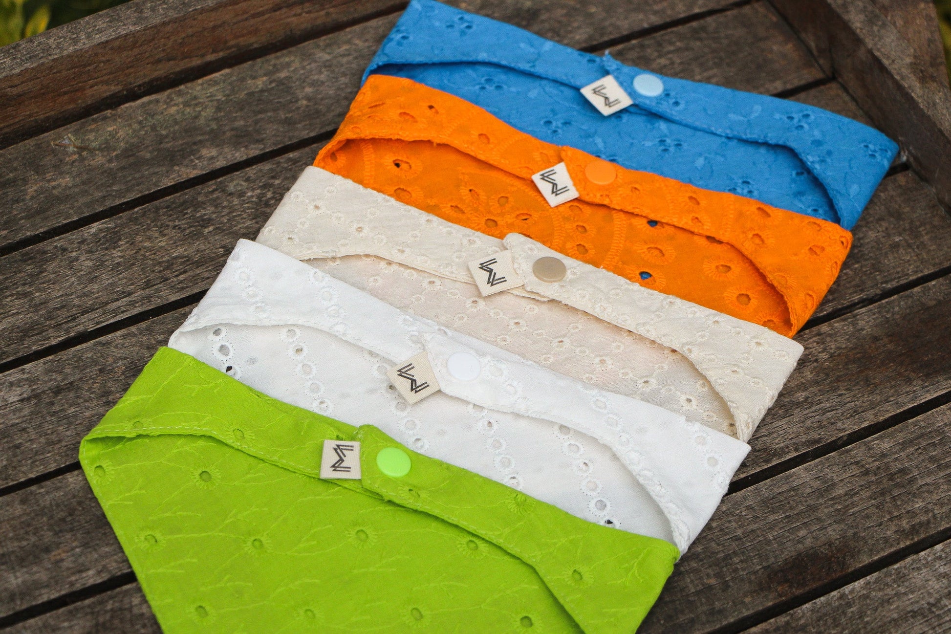 Explore the Eyelet Dog Bandana in a rainbow of colors—classic white, cool blue, bright orange, subtle beige, and vibrant green. Each color showcases our signature lace detailing for a pop of style.