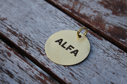 Round brass pet ID tag with custom engraving.